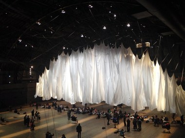 Ann Hamilton's art installation "the event of a thread" has taken over the Park Avenue Armory between now and January 6. A gigantic white curtain bisects the space, rising and falling and billowing in response to the movements of audience members swinging on 42 swings hung from the ceiling.